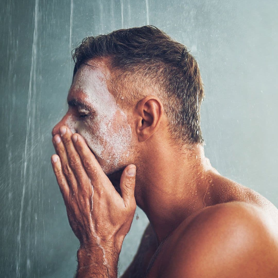 A man in the shower using the scrub