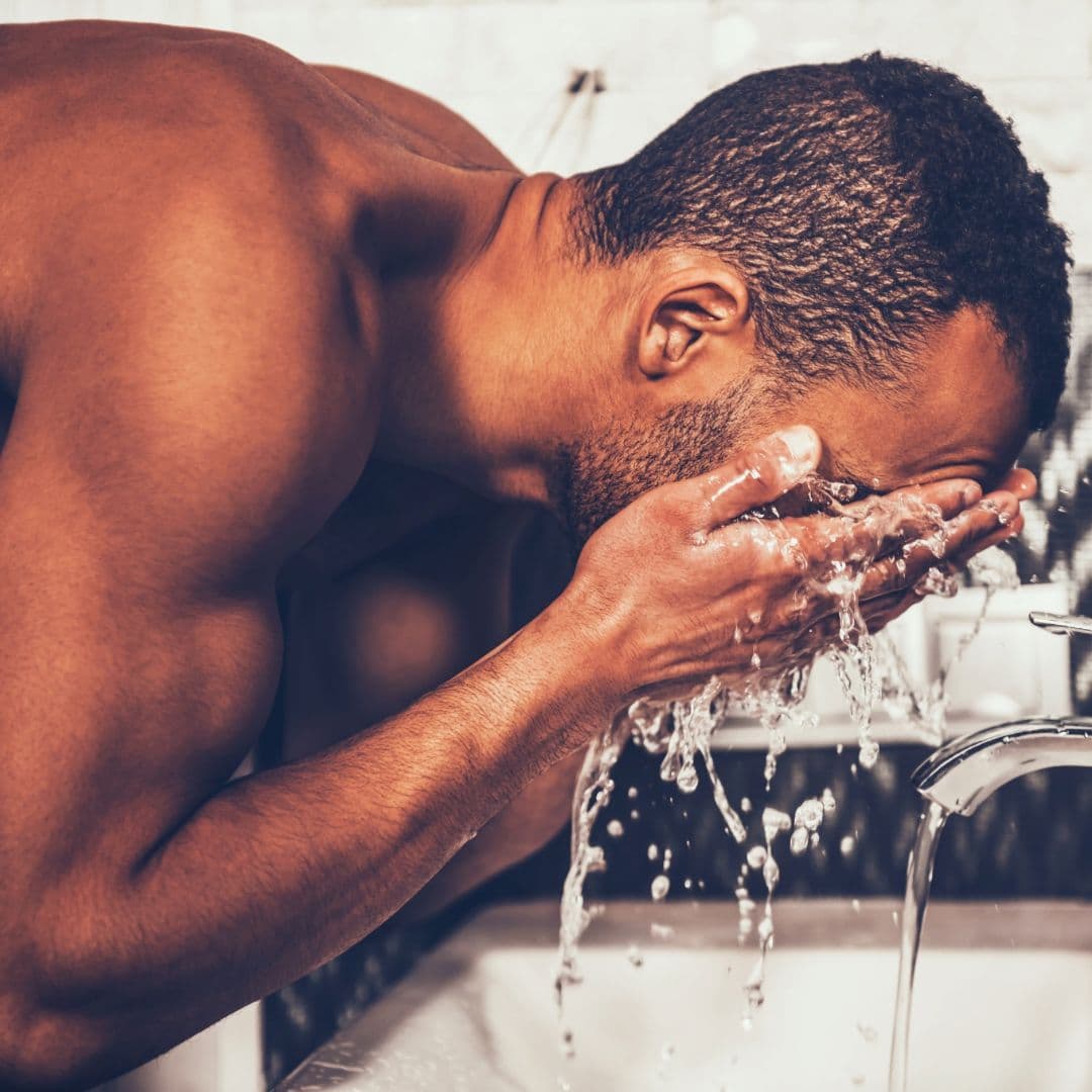 A man washing his face at the sink